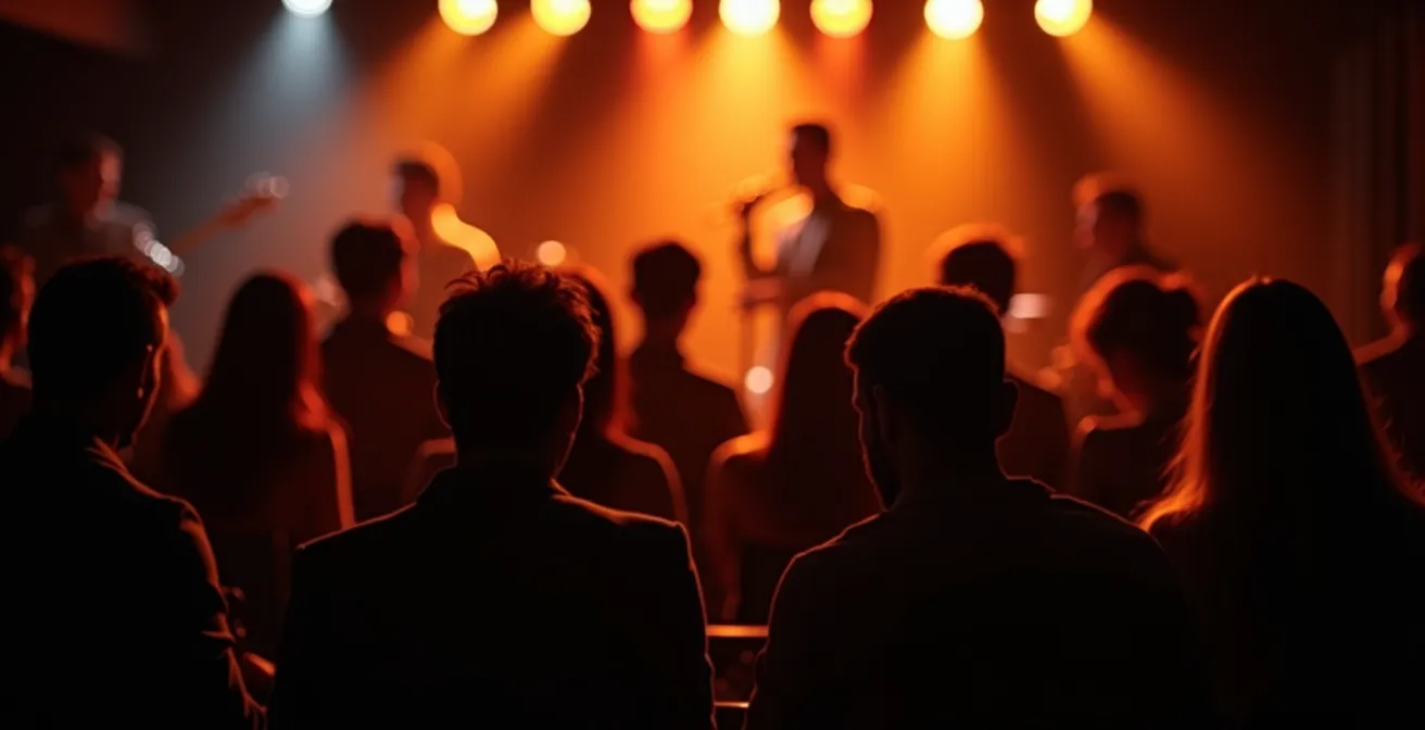 Dimly lit jazz club interior showing musicians on stage with audience in foreground